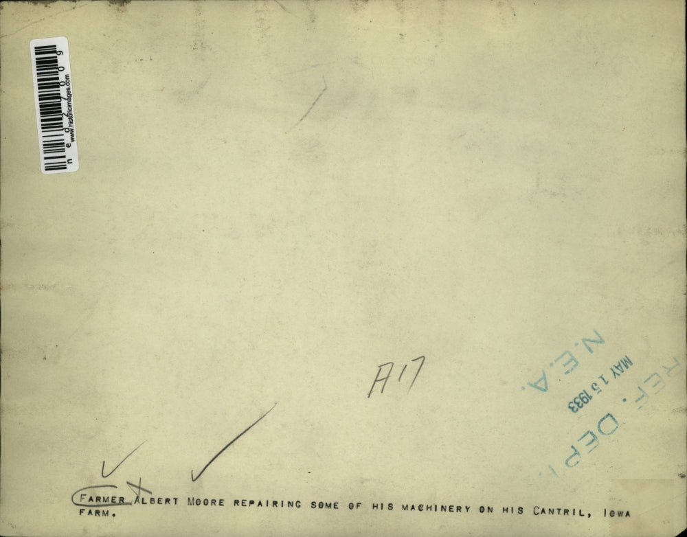 1933 Press Photo Farmer Albert Moore repairing some of his machinery on his