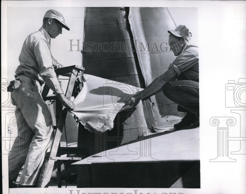1950 Press Photo Navy Workers Peel Off Protective Plastic Skin