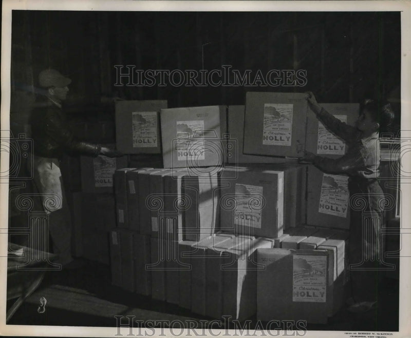 Load image into Gallery viewer, 1946 Press Photo C. McClung &amp; schoolboy helper stack packages of holly wreaths
