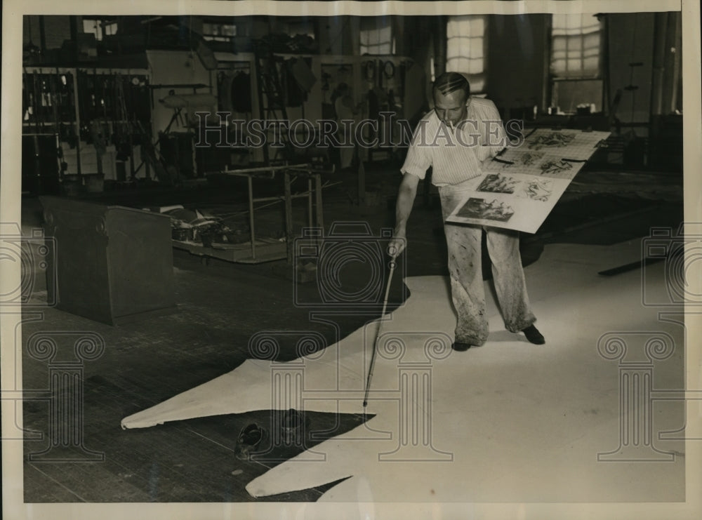 1938 Press Photo Artist removes shoes and steps on cloth drops as he outlines