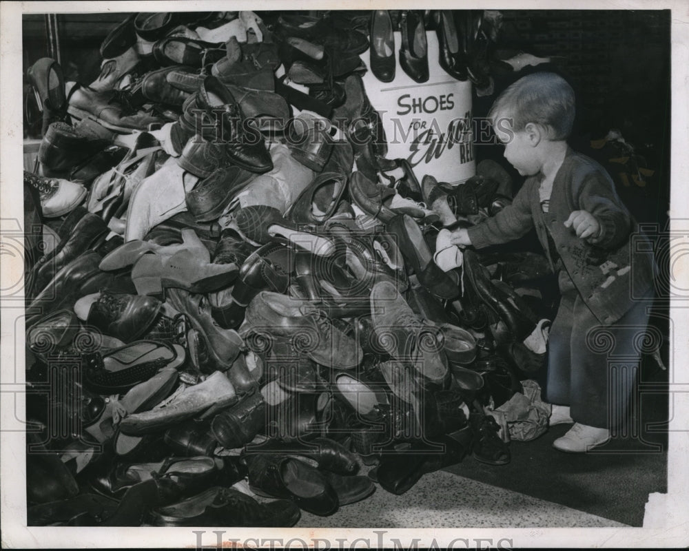 1947 Press Photo Dennis Henning adds contribution to pile of used footwear