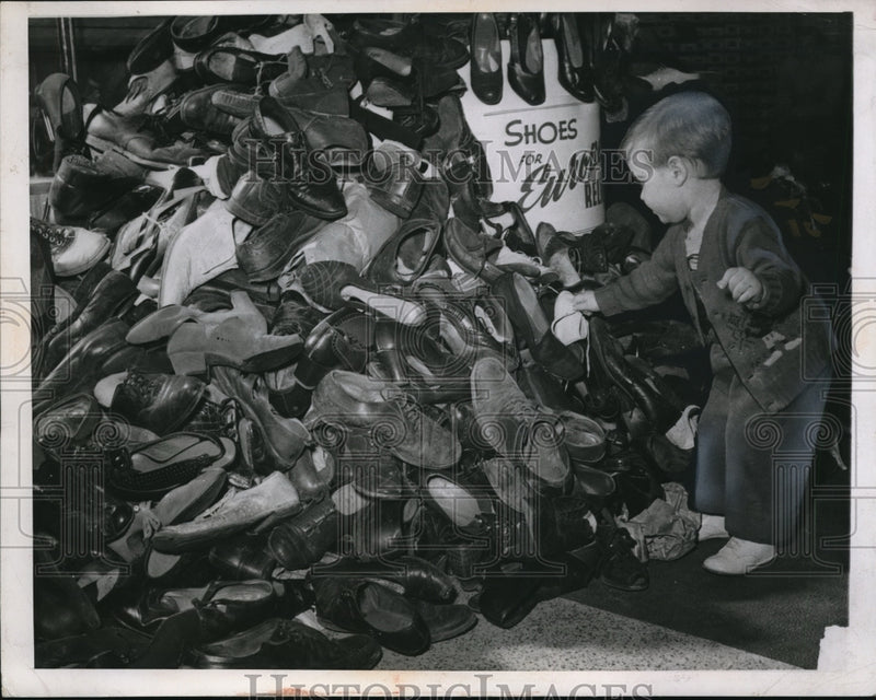 Load image into Gallery viewer, 1947 Press Photo Dennis Henning adds contribution to pile of used footwear
