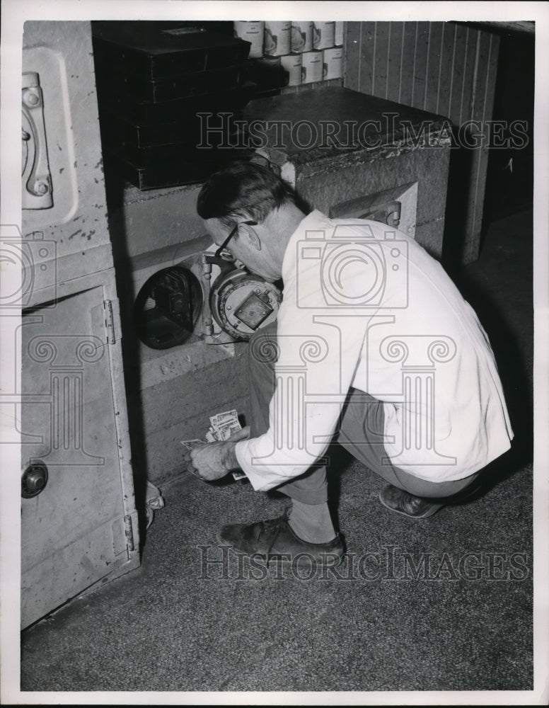 1955 Press Photo Supermarket Manager checking the money left after the robbery.