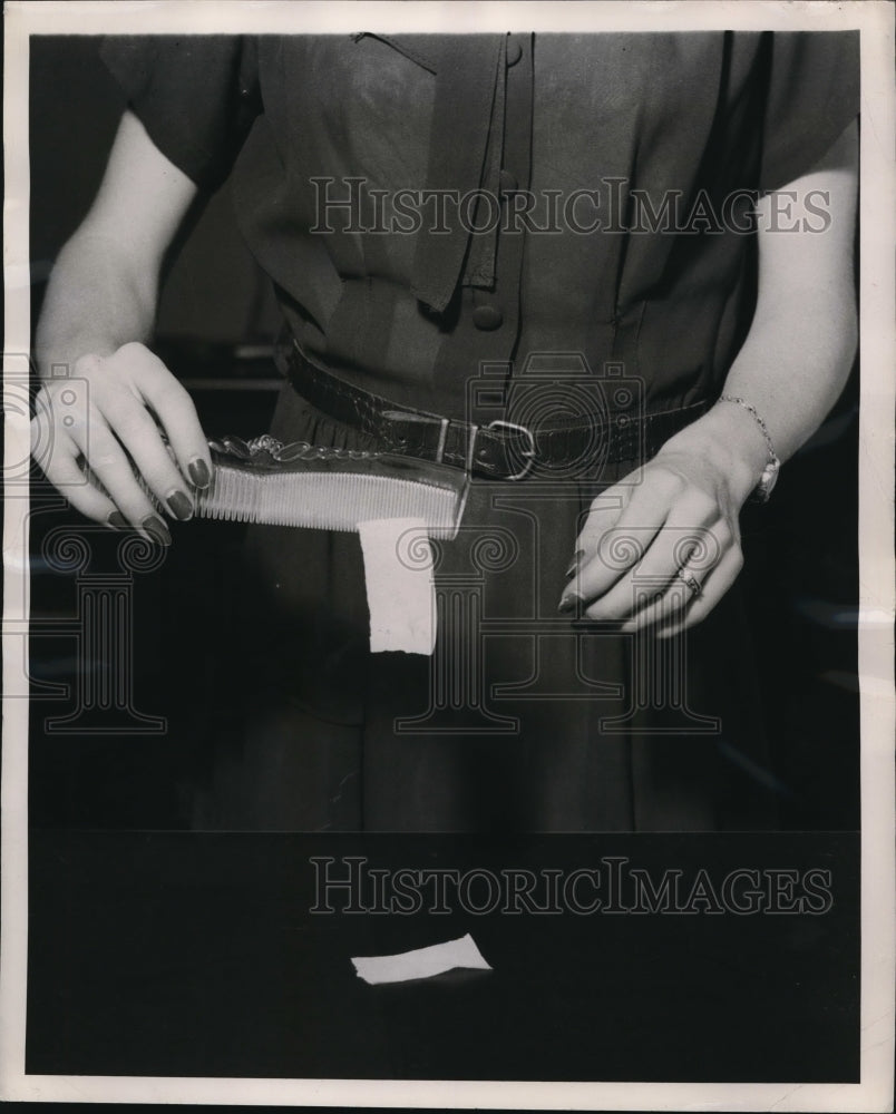 1948 Press Photo Comb picking up a piece of paper