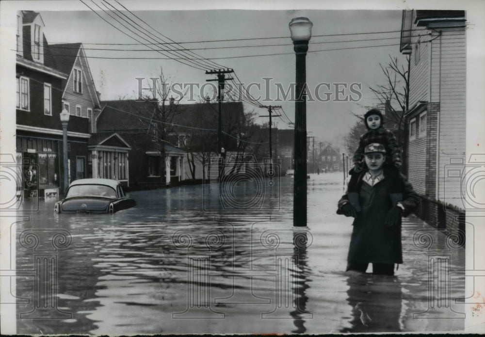 1956 Press Photo Man carries child thru floodwaters in home town USA