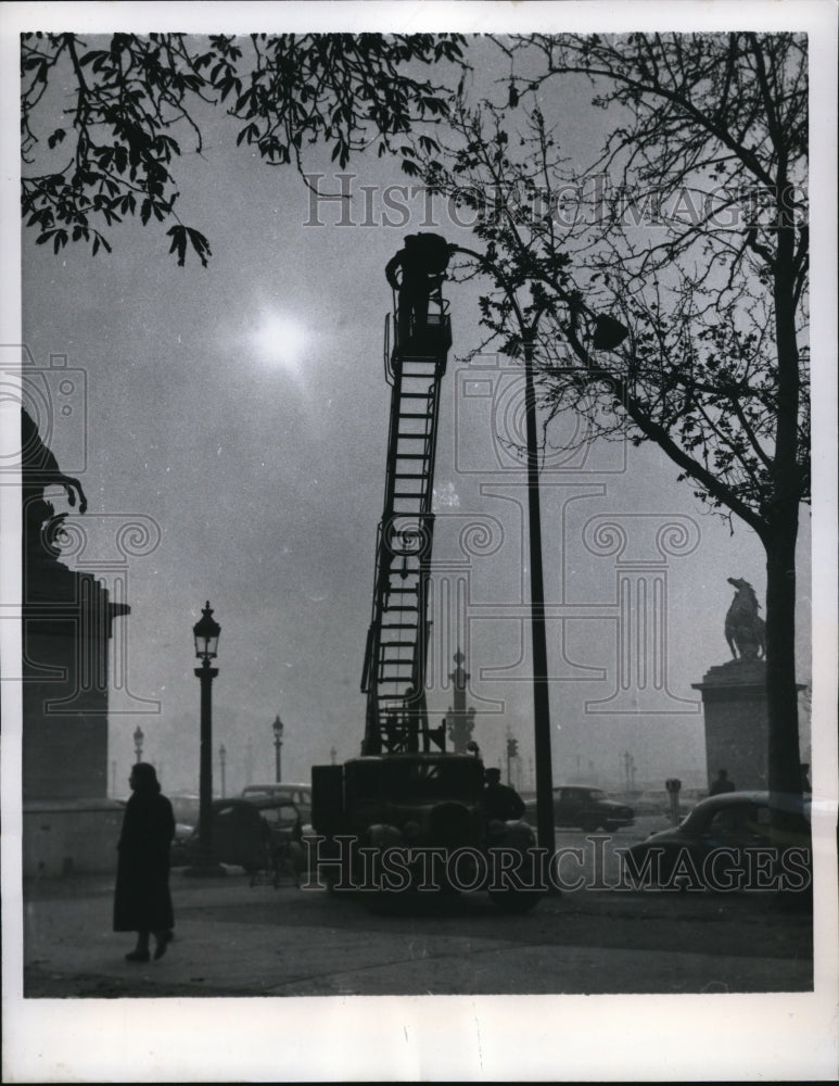 1957 Press Photo Paris a workman is cleaning a street lamp on the Place De La