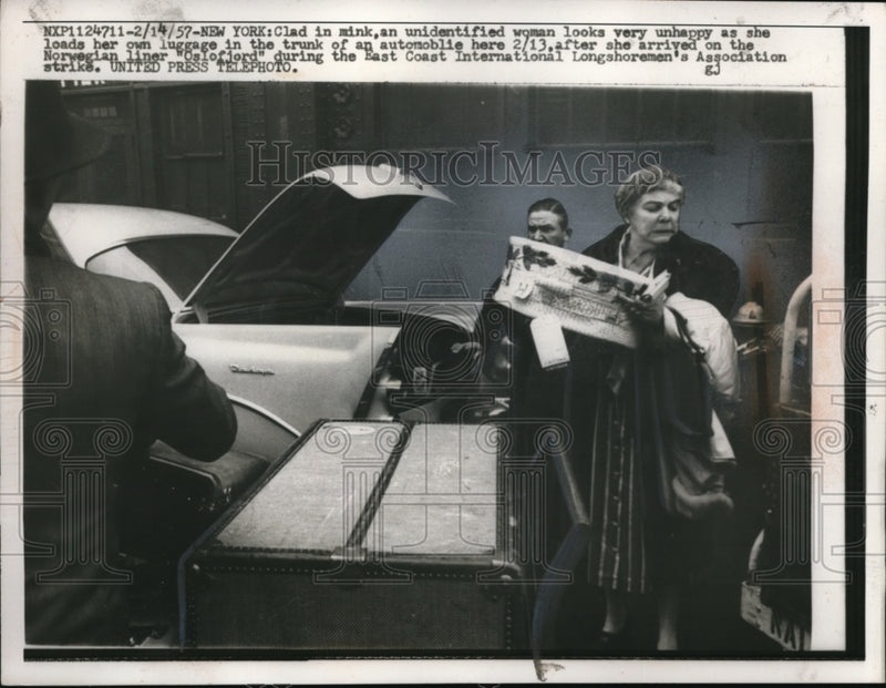 Load image into Gallery viewer, 1957 Press Photo Unhappy women loads luggage in trunk of automobile
