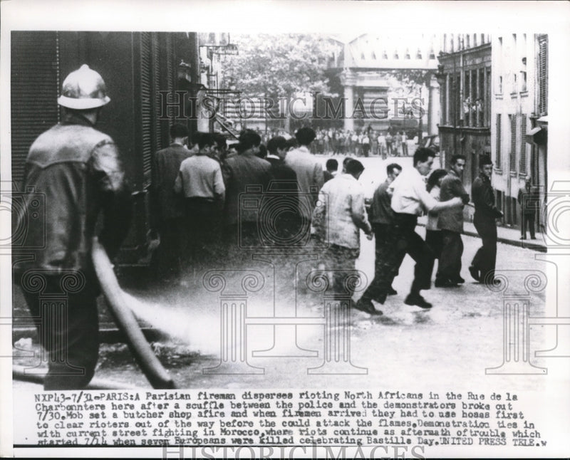 Load image into Gallery viewer, 1955 Press Photo Fireman disperses rioting Africans in Rue de la Charbonntere
