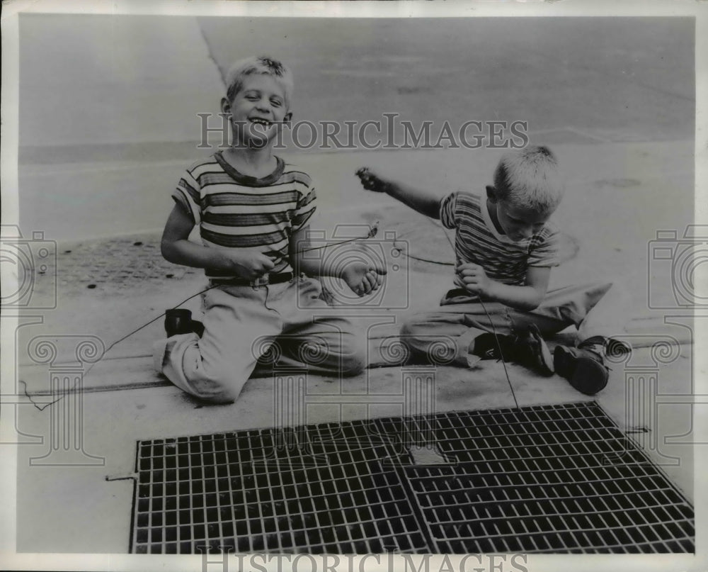 1957 Press Photo Cleveland Ohio Andy & Allen Staursky Jr get coins from grates