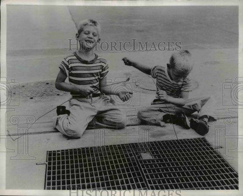 Load image into Gallery viewer, 1957 Press Photo Cleveland Ohio Andy &amp; Allen Staursky Jr get coins from grates
