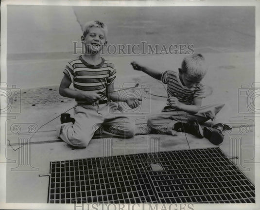 1957 Press Photo Cleveland Ohio Andy & Allen Staursky Jr get coins from grates