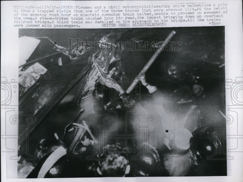 Load image into Gallery viewer, 1957 Press Photo Firemen and a civil motorcyclist use a pole to help a victim
