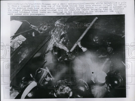1957 Press Photo Firemen and a civil motorcyclist use a pole to help a victim