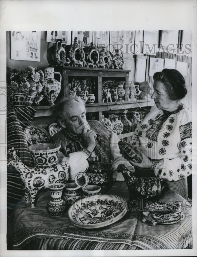Load image into Gallery viewer, 1958 Press Photo Evgenye Saigaidachni and wife at home filled with wood carvings
