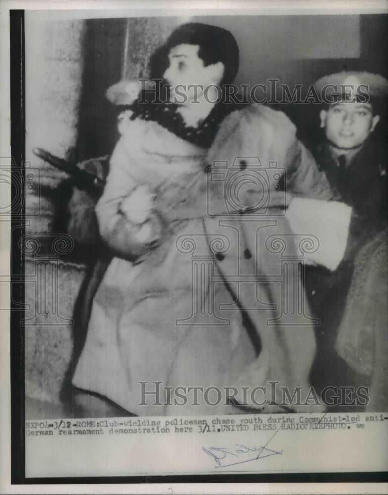 1955 Press Photo Club wielding policeman chased a youth at a demonstration
