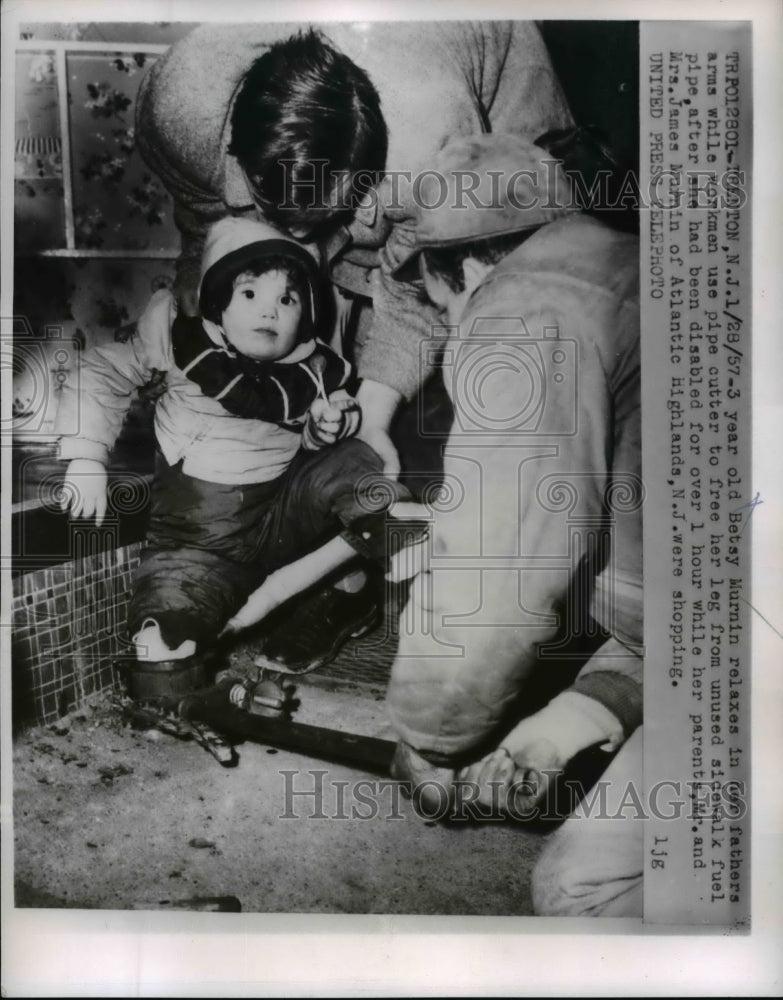 Load image into Gallery viewer, 1957 Press Photo Betty Murnin being resued by her father by using a pipe cutter
