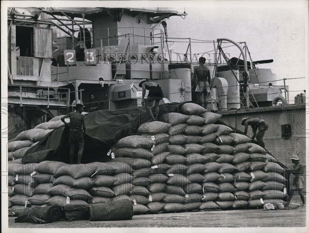 1964 Press Photo of workers covering bags of rice that are being sent to Saigon