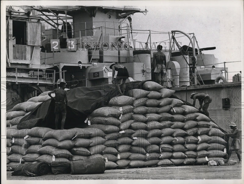 Load image into Gallery viewer, 1964 Press Photo of workers covering bags of rice that are being sent to Saigon
