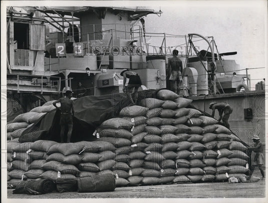1964 Press Photo of workers covering bags of rice that are being sent to Saigon