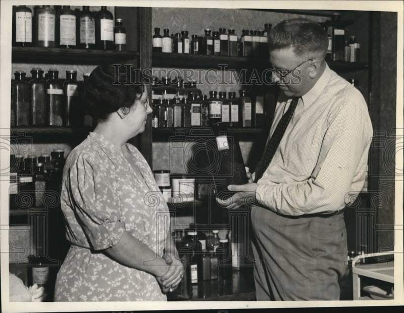 Load image into Gallery viewer, 1938 Press Photo Mrs. Lora La Mavce and Henry West examine pill bottle
