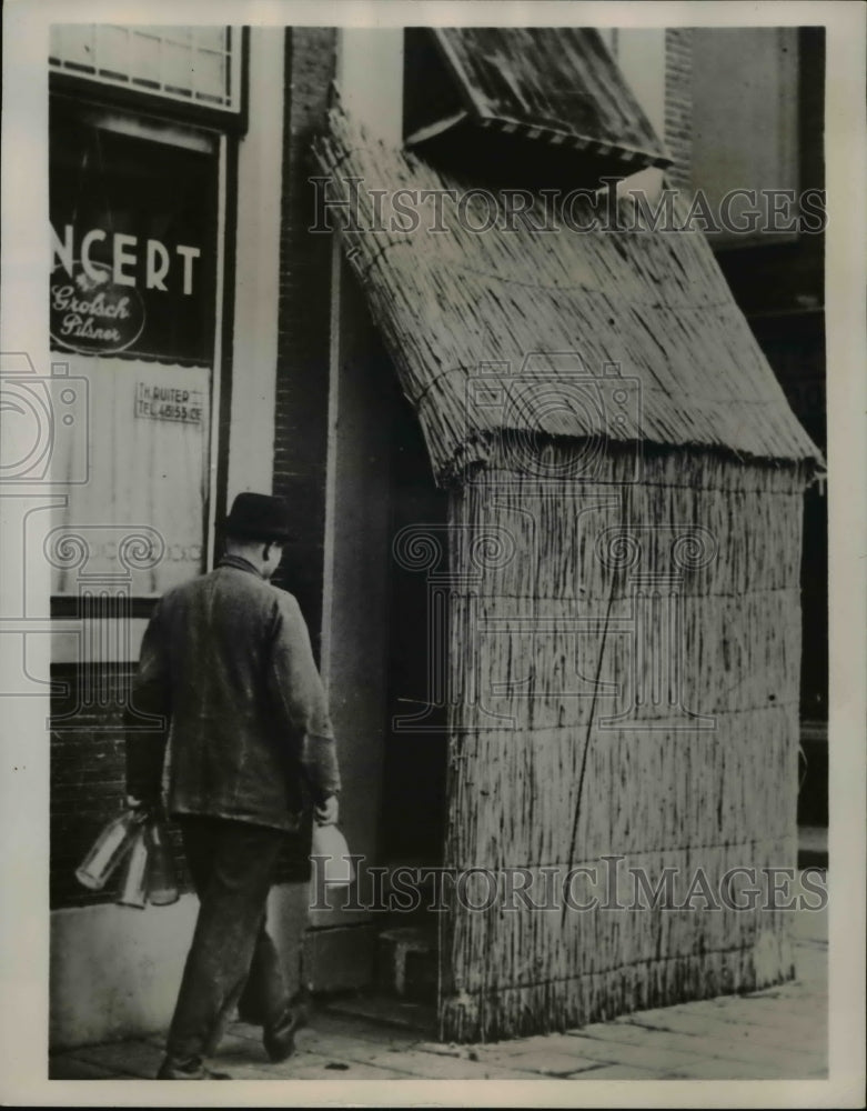 1940 Press Photo Inn Keeper in Holland Rigs Door Shield Blocks Out Light at Nigh