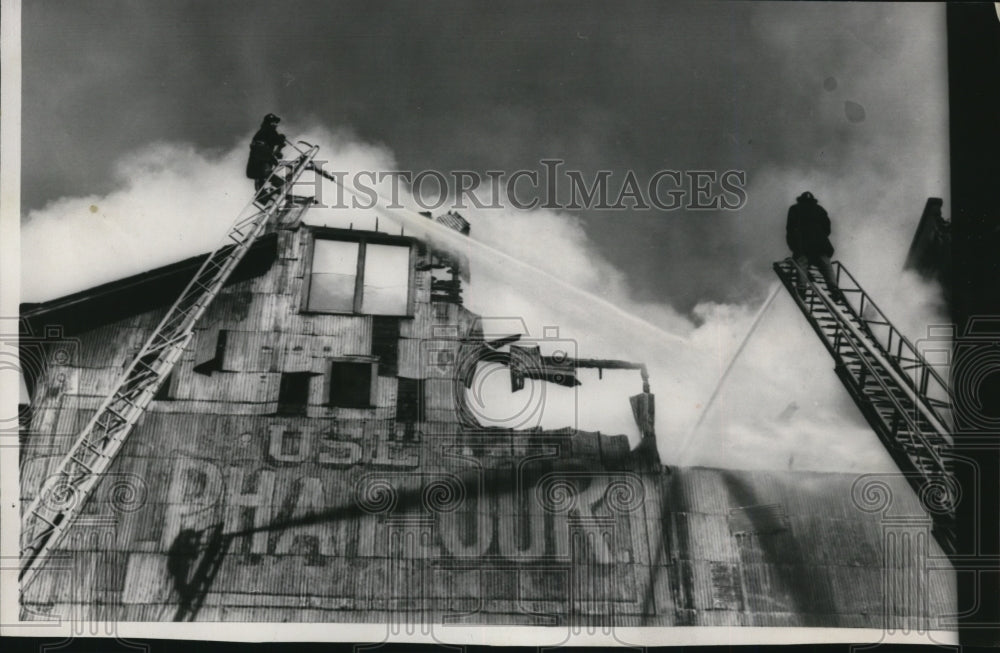 1958 Press Photo Firemen Pour Water onto the Flaming Roof of Gwinn Bros. Feed