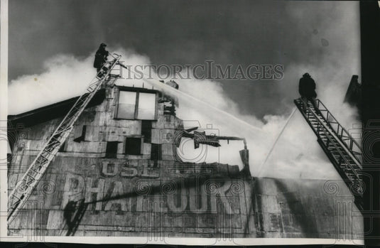 1958 Press Photo Firemen Pour Water onto the Flaming Roof of Gwinn Bros. Feed