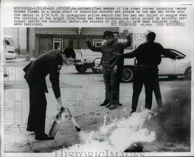 Load image into Gallery viewer, 1969 Press Photo Member of Armed Forces Induction Center Douses Flames in Sheaf
