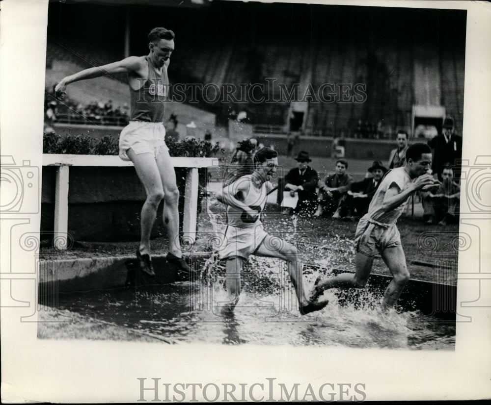 1938 Press Photo Several runners in steeplechase event take jump at Penn Relays- Historic Images