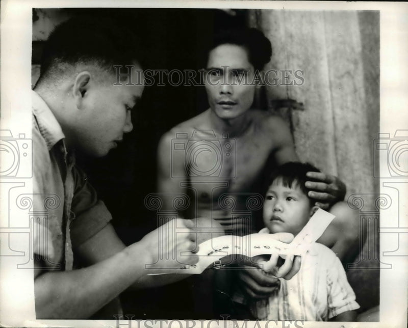 Load image into Gallery viewer, 1970 Press Photo Malaysian father learn to administer Malaria medicine to his
