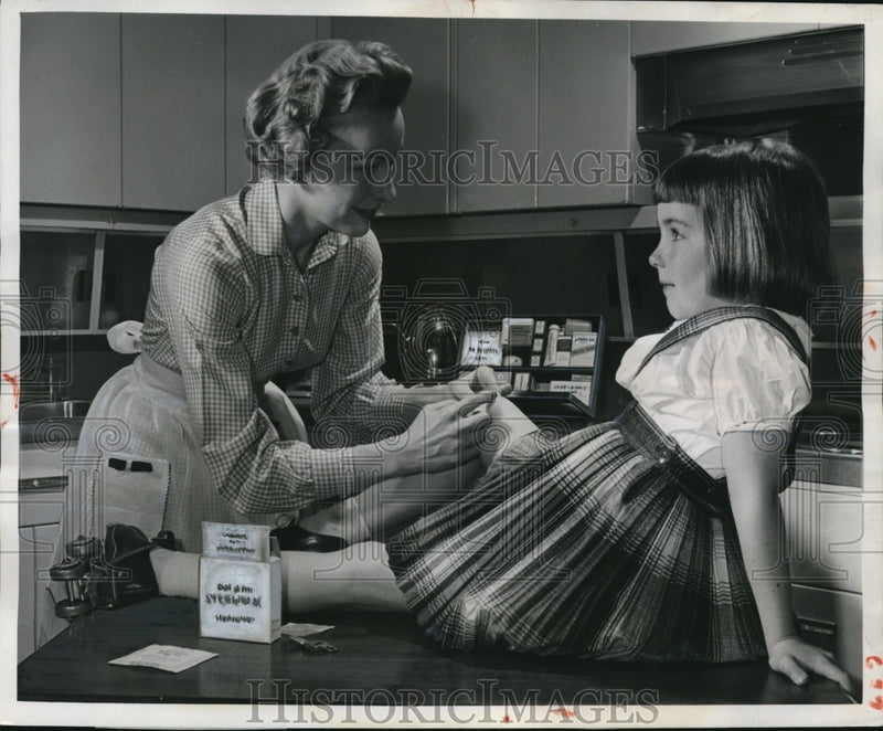 Load image into Gallery viewer, 1958 Press Photo Woman bandages daughters knee with sterile gauze
