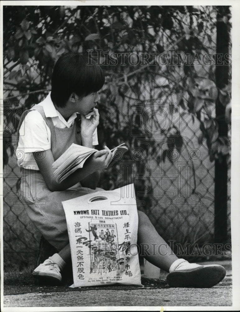 Load image into Gallery viewer, 1971 Press Photo Kuala Lumpur Malaysia schoolgirl waits for ride after class
