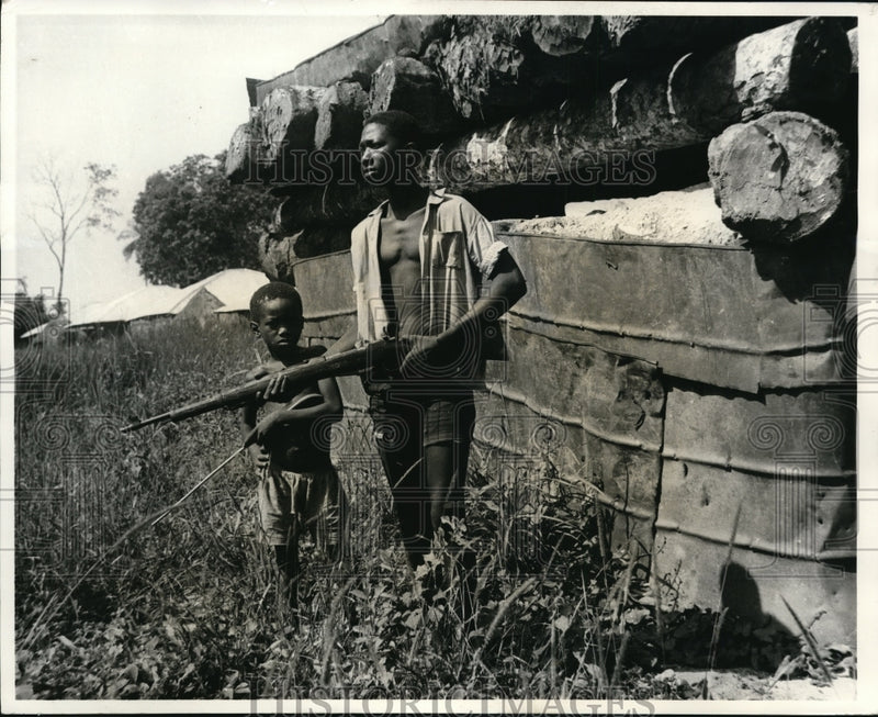 Load image into Gallery viewer, 1969 Press Photo Armed Insurgent &amp; Boy Guarding Rebel Outpost, Portuguese Guinea
