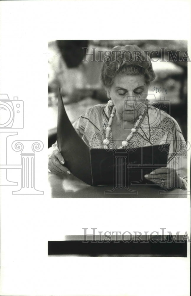 1987 Press Photo A customer looks over menu at Airline Motors Restaurant.- Historic Images