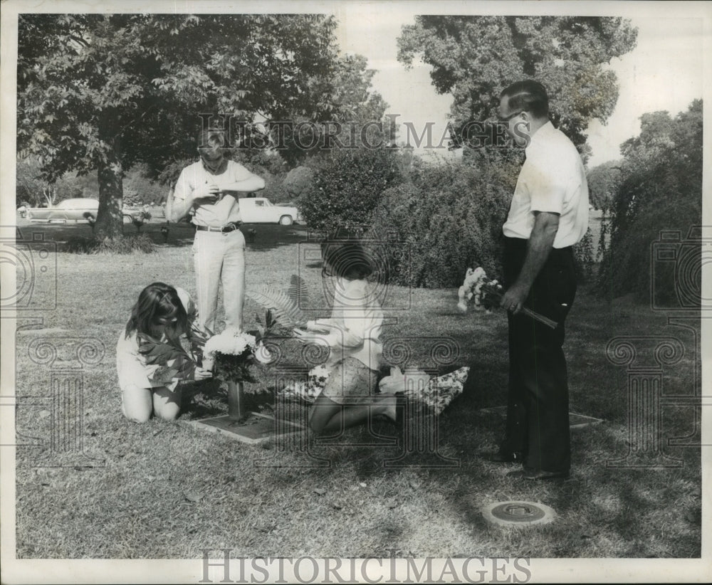 1968 Press Photo All Saints Day - A family places flowers on grave site.- Historic Images