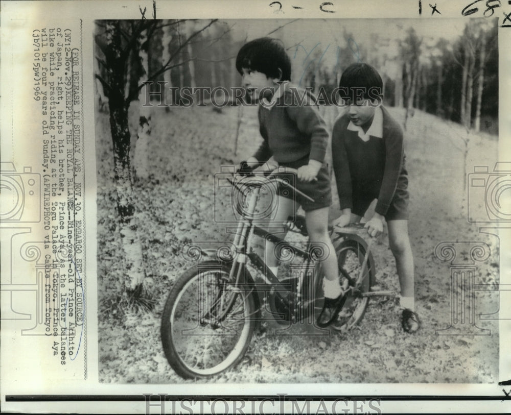 1969 Press Photo 9 year old Prince Akihito helps brother Prince Aya on bicycle.- Historic Images