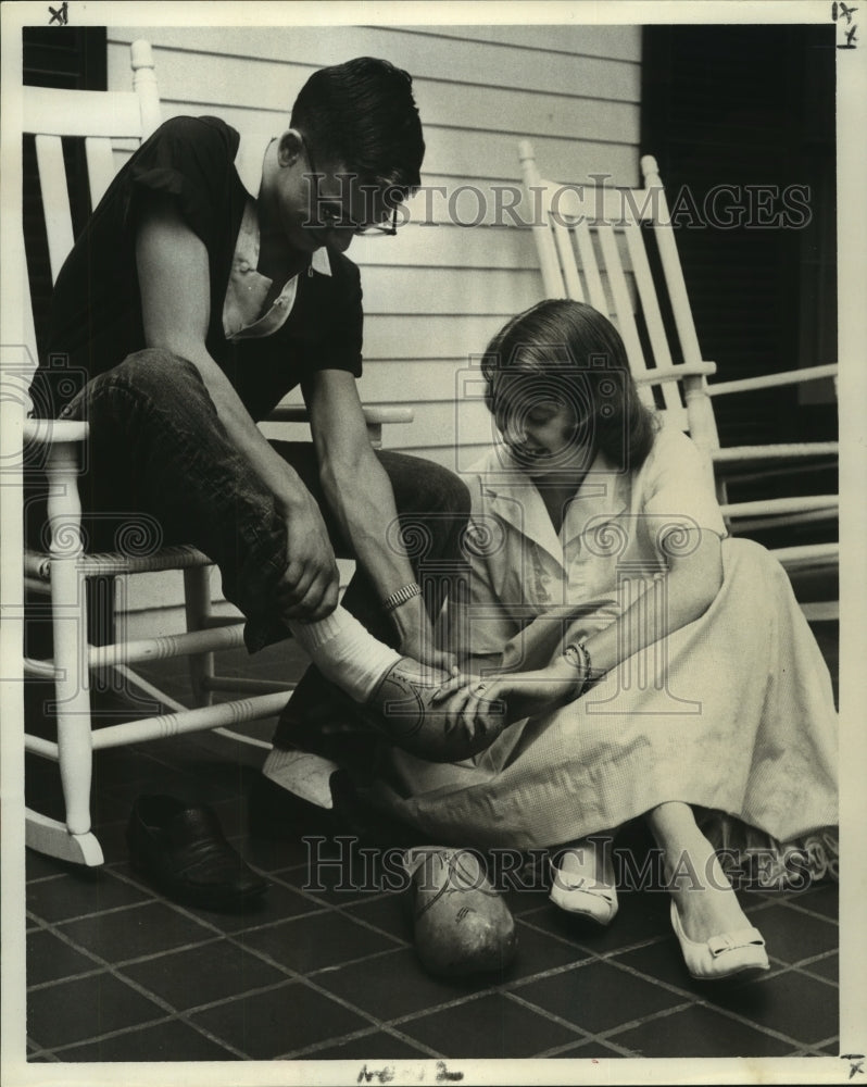 1959 Press Photo Sari Duvekot tries wooden shoes on feet of Tommy Freeland- Historic Images