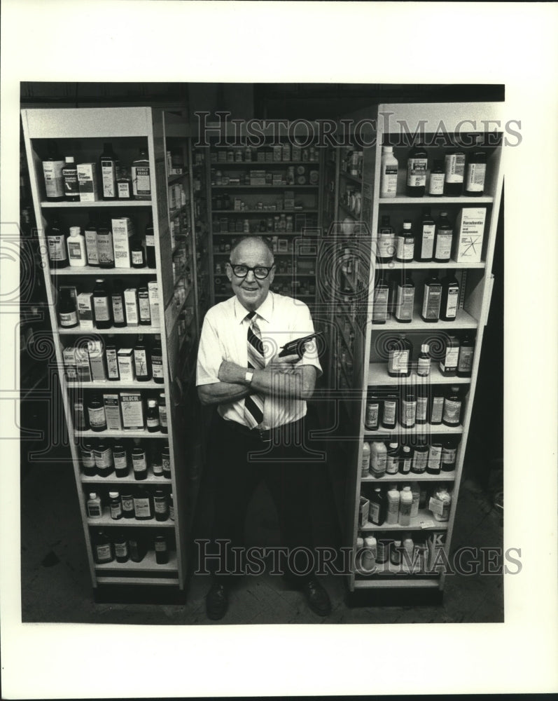 1982 Press Photo Lloyd Folse stands in pharmacy holding a gun- Historic Images