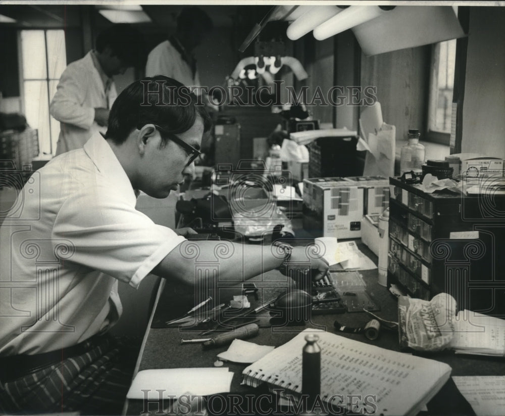 1974 Press Photo E. ishiwatari repairs camera at Sears facility in trade zone.- Historic Images