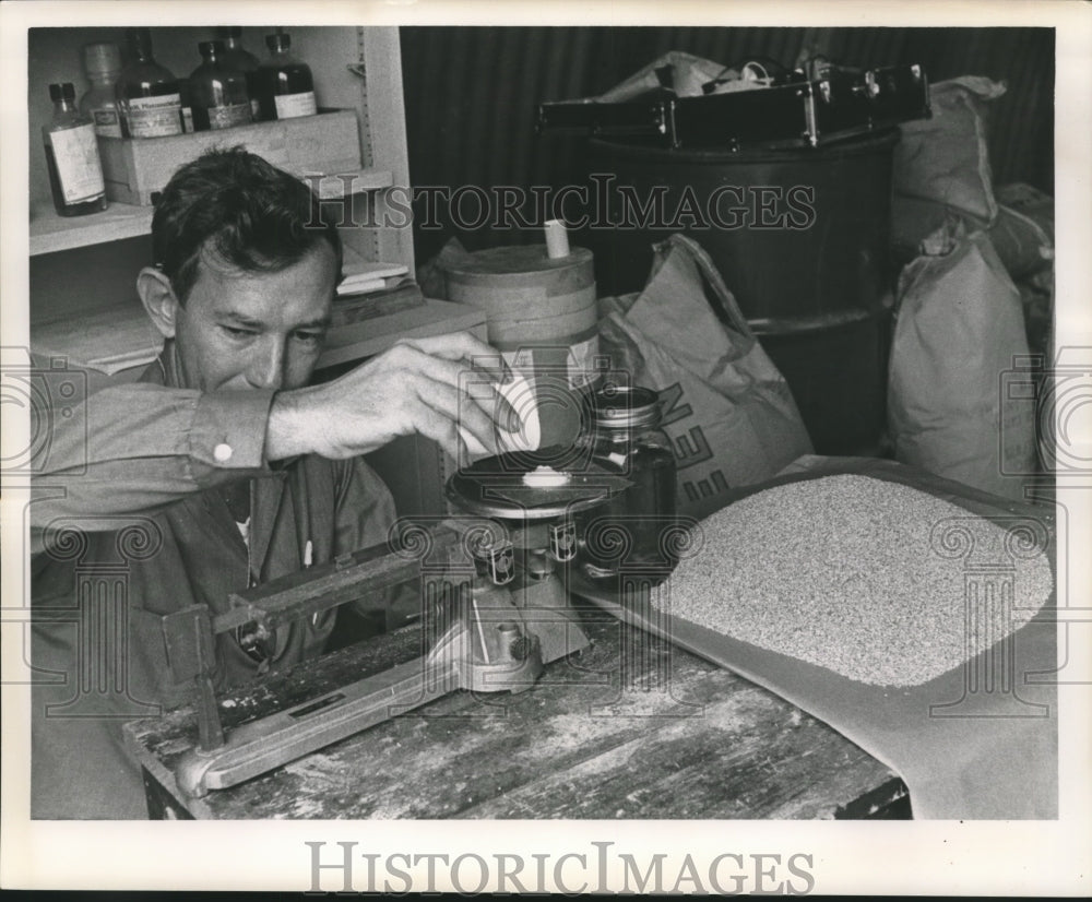 1963 Press Photo Farmer weighs additive for his seed. - nob10774