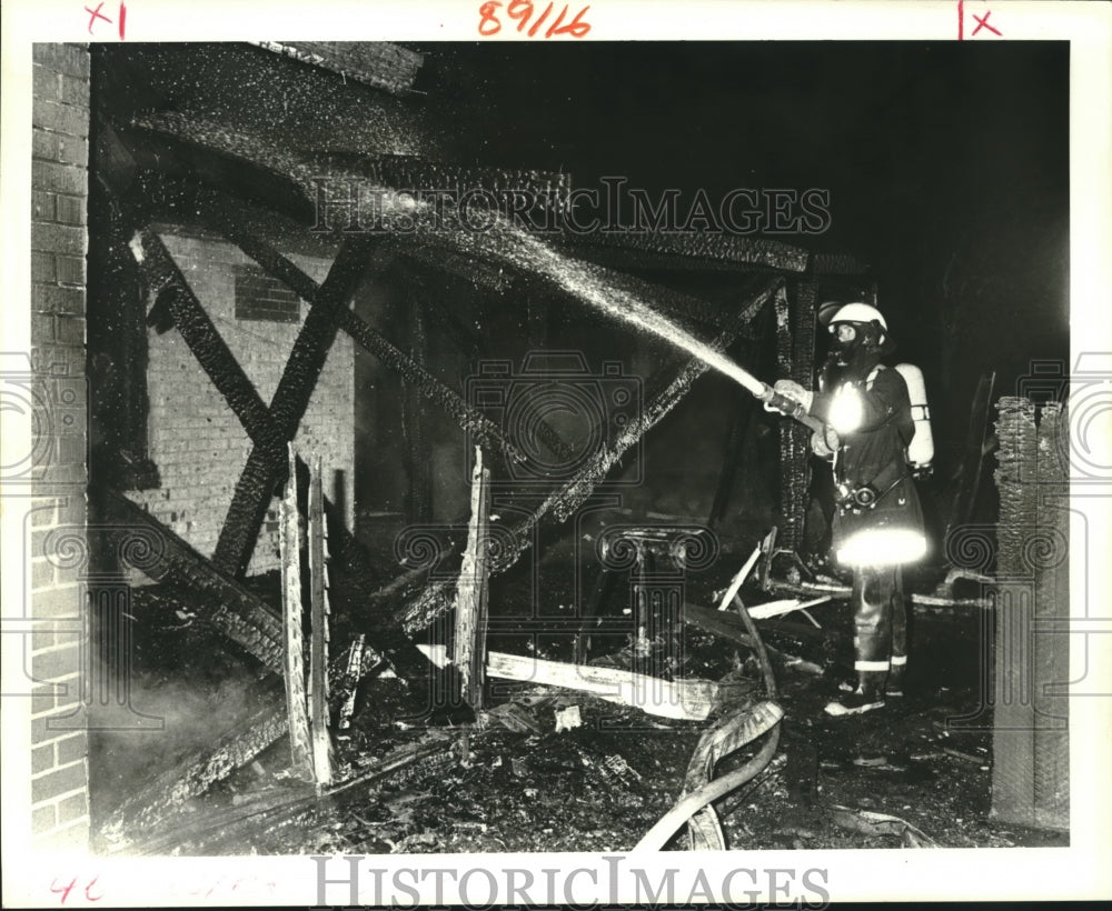 1987 Press Photo Third district fireman hoses rear of home in Metairie- Historic Images