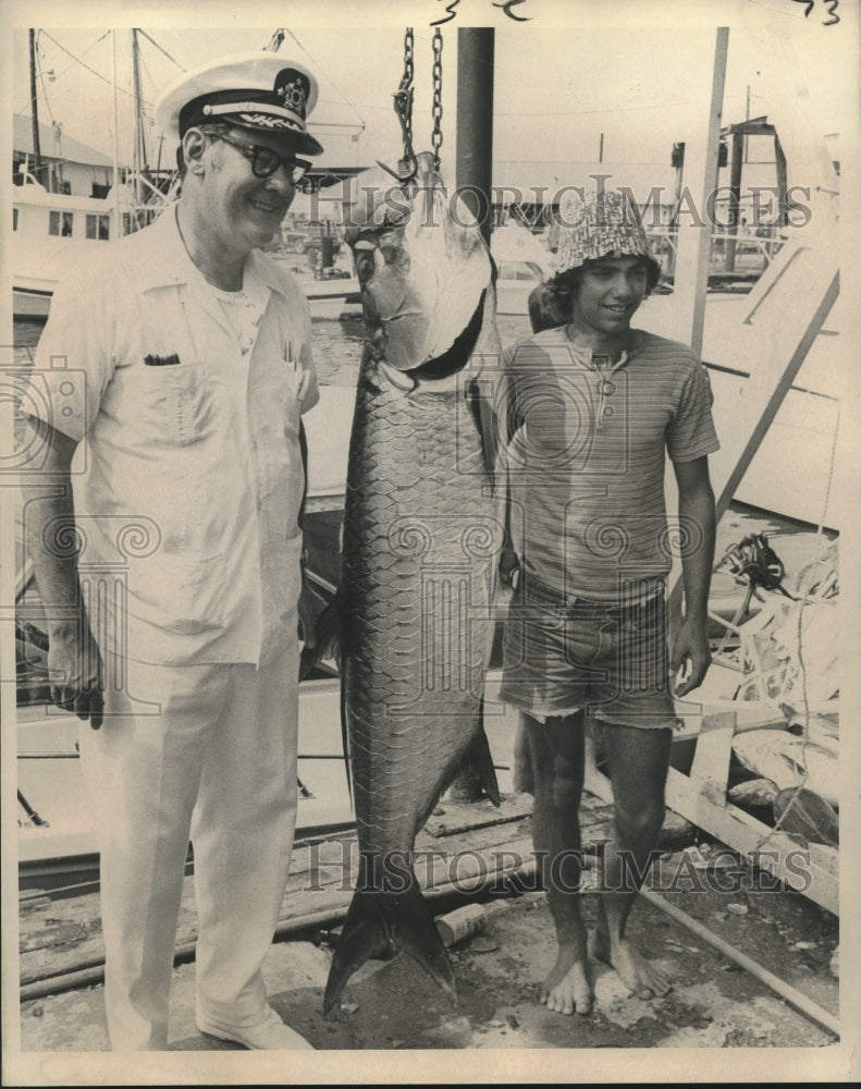 1973 Press Photo Dr. Flores looks at tarpon caught by Ricky Guidry.- Historic Images