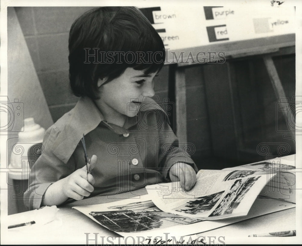 1975 Press Photo Young Schoolgirl Searches Magazines for Pictures to Cut Out- Historic Images