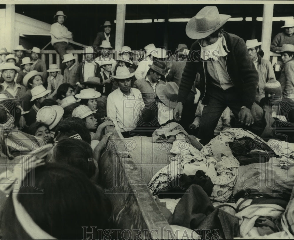 1976 Press Photo Guatemala Earthquake Survivors Gather Around Man with Clothing- Historic Images