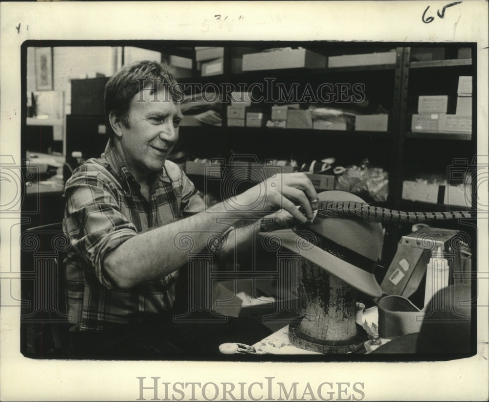 1978 Press Photo Milliner Hann sticks peacock feather in hat from his collection- Historic Images