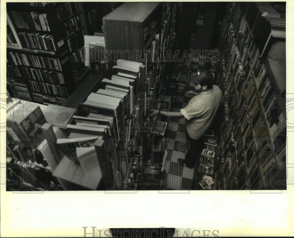 1988 Press Photo Gerry Hunsinger browses stacks of books at Herget&#39;s shop- Historic Images