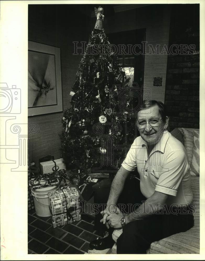 1985 Press Photo Burton G. Klein sits next to Christmas tree in his home