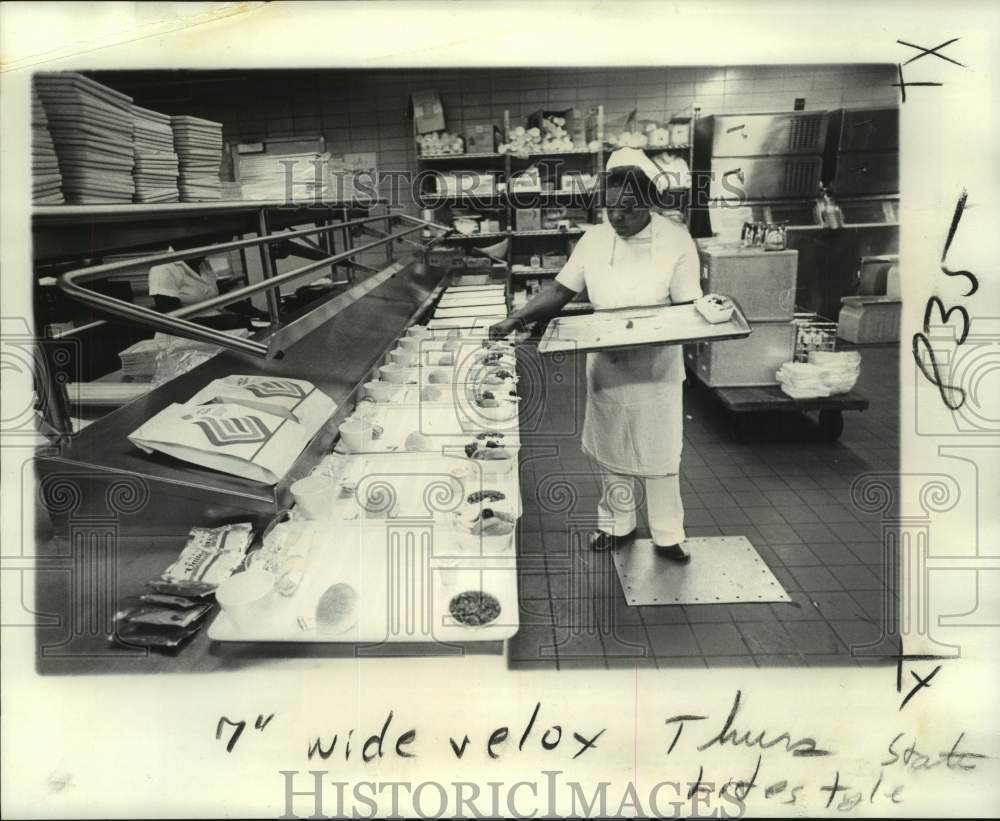 1974 Press Photo Edna Joseph, Host International employee fills flight trays- Historic Images