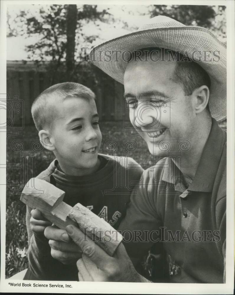 1988 Press Photo Astronaut James McDivitt checks his son Michael's wood carving- Historic Images