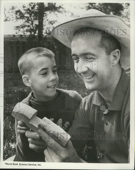 1988 Press Photo Astronaut James McDivitt checks his son Michael's wood carving- Historic Images